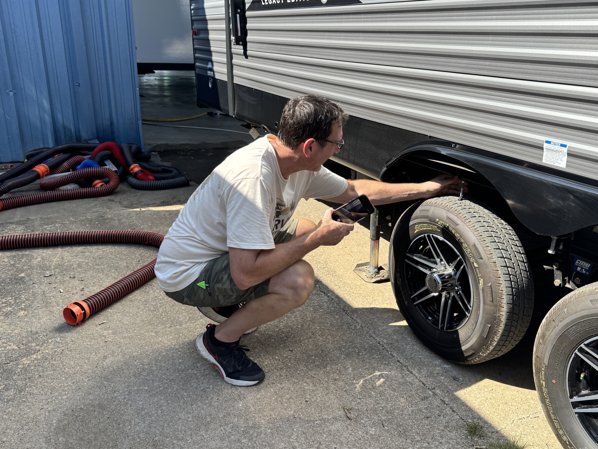 An OZ RVS technician checking a travel trailer's tire before a trip